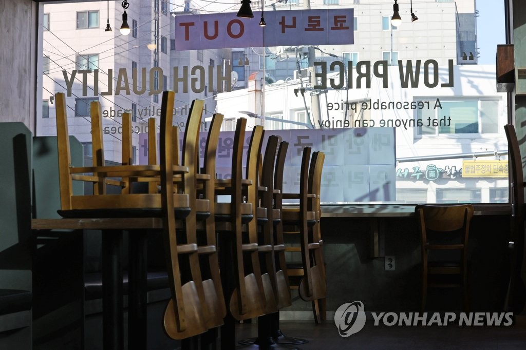 Chairs are turned upside down on tables inside a coffee shop in southern Seoul on Jan. 6, 2021, amid the government's COVID-19 restrictions on dining in at cafes. (Yonhap)