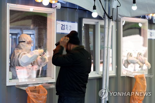 This photo taken on Jan. 17, 2021, shows a health worker collecting a sample from a citizen for the novel coronavirus test at a makeshift testing facility in Seoul. (Yonhap)