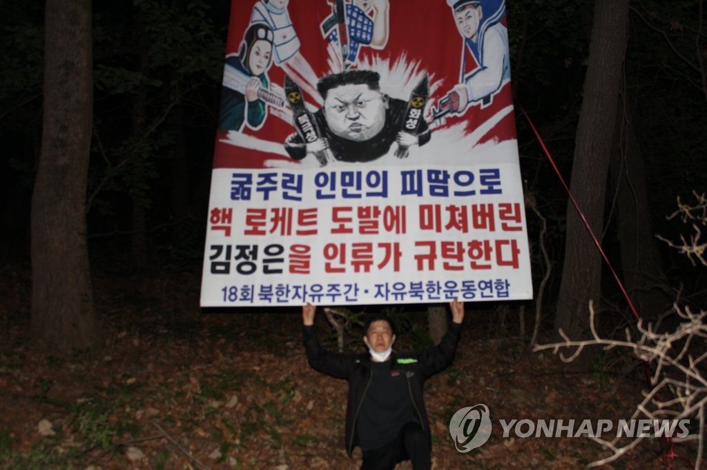 Park Sang-hak, an anti-Pyongyang activist, holds up a placard denouncing North Korean leader Kim Jong-un, in this photo provided by his activist group. (PHOTO NOT FOR SALE) (Yonhap)