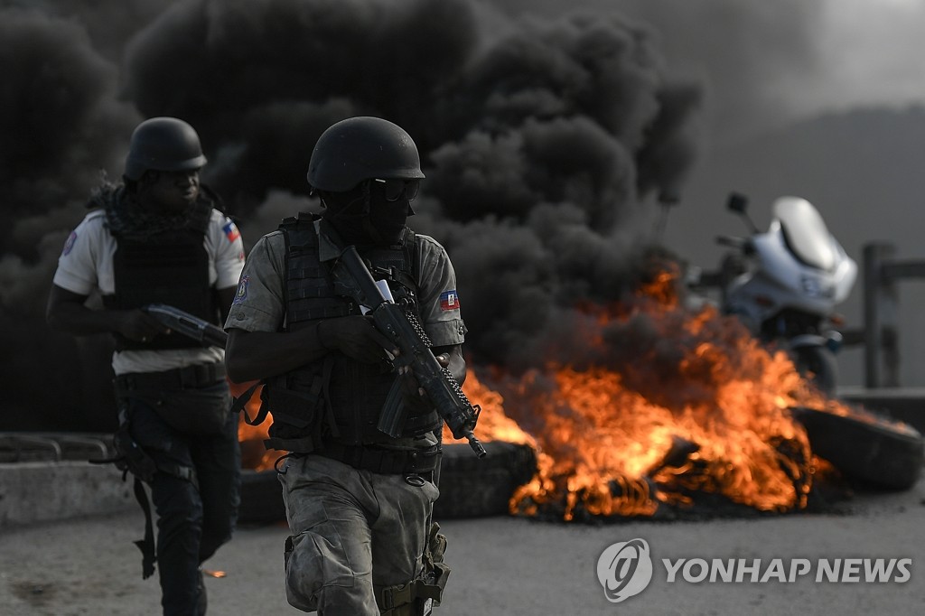 불붙은 바리케이드로부터 피신하는 아이티 무장 경찰