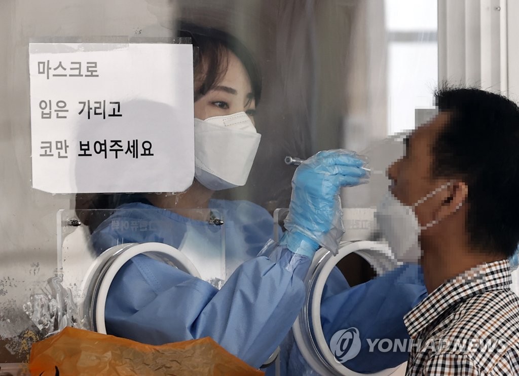 A health worker in a protective suit collects a sample from a citizen at a makeshift COVID-19 testing clinic in Seoul on Oct. 11, 2021. (Yonhap)