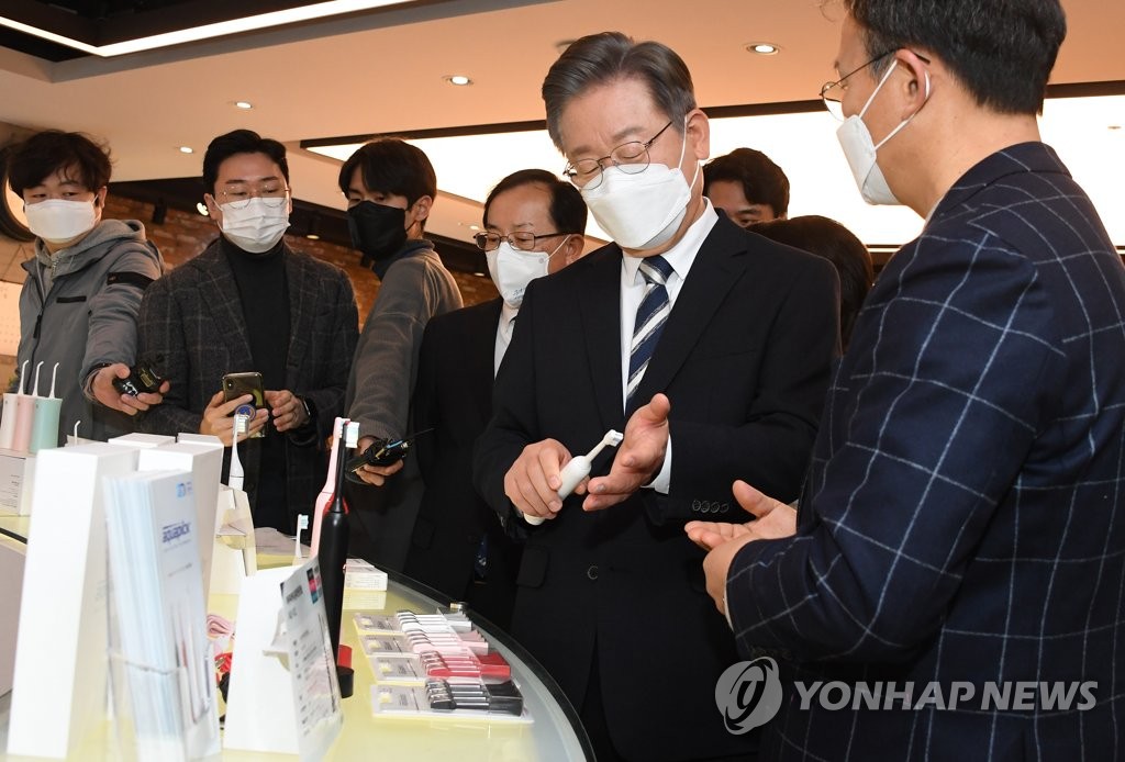 Lee Jae-myung (2nd from R), the presidential nominee of the Democratic Party, takes a look at products made by small and medium-sized businesses at an industrial complex in southwestern Seoul on Dec. 8, 2021. (Pool photo) (Yonhap)
