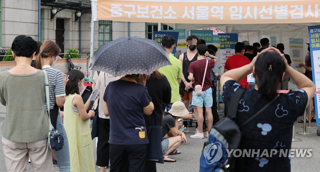 People wait to take COVID-19 tests at a makeshift testing center near Seoul Station in central Seoul on Aug. 14, 2022. (Yonhap)
