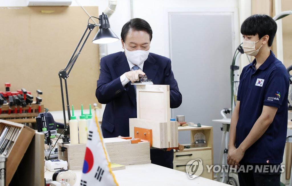 El presidente surcoreano, Yoon Suk-yeol (izda.), lija madera, el 14 de septiembre de 2022, durante una visita al Instituto Global para la Transferencia de Habilidades en Incheon, al oeste de Seúl.