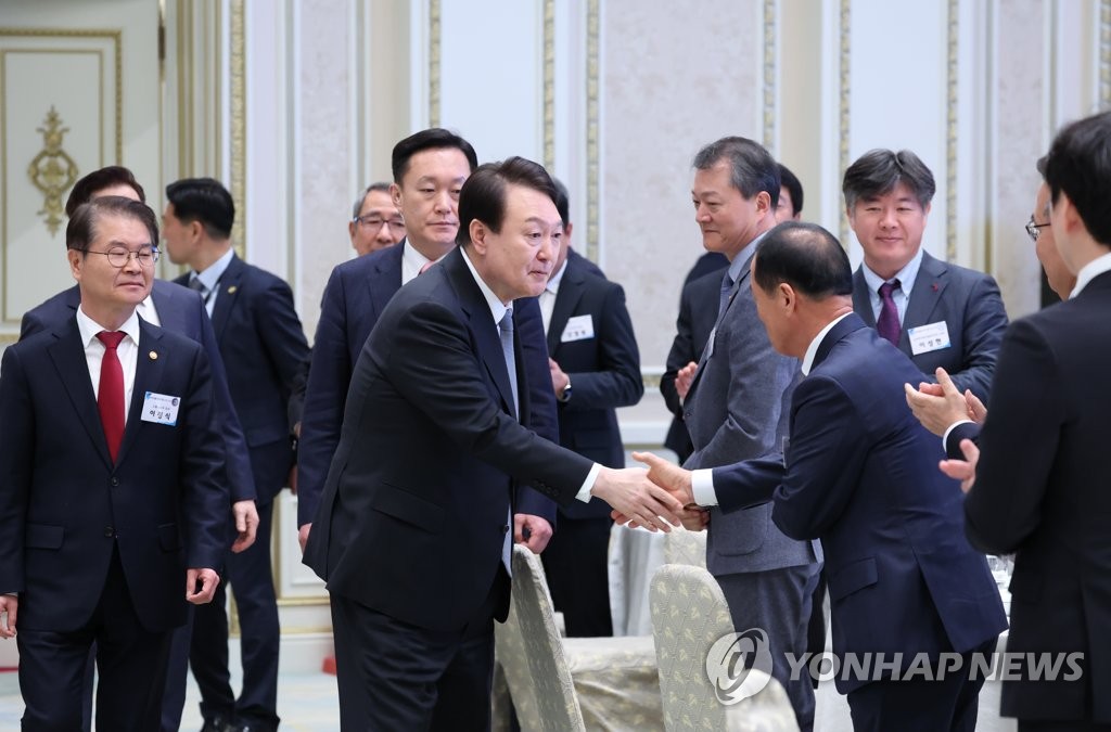 El presidente surcoreano, Yoon Suk Yeol (2º por la izda.), estrecha la mano de un asistente, en un almuerzo de trabajo para directores ejecutivos de empresas reconocidas por la creación de empleos, el 14 de marzo de 2023, en el antiguo complejo presidencial, Cheong Wa Dae, en Seúl.
