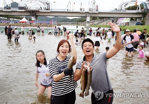 Visitors celebrate after catching trout with their bare hands during the 20th Muju Firefly Festival in Muju, North Jeolla Province, on Sept. 4, 2016. (Yonhap)