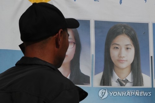 In this photo taken on May 19, 2017, the father of Sewol ferry victim Heo Da-yoon talks on the phone in front of his daughter's photo in Mokpo, some 410 kilometers south of Seoul. (Yonhap) 