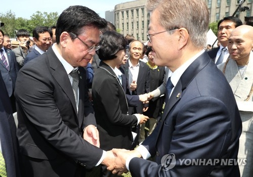 President Moon Jae-in (R) shakes hands with Rep. Chung Woo-taik, floor leader and acting chief of the main opposition Liberty Korea Party, at a ceremony held in downtown Seoul on June 10, 2017, marking the 1987 democratic movement. (Yonhap)