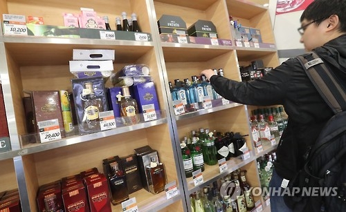 In this file photo taken on Nov. 11, 2016, a consumer looks at bottles of liquor at a supermarket in Seoul. (Yonhap) 