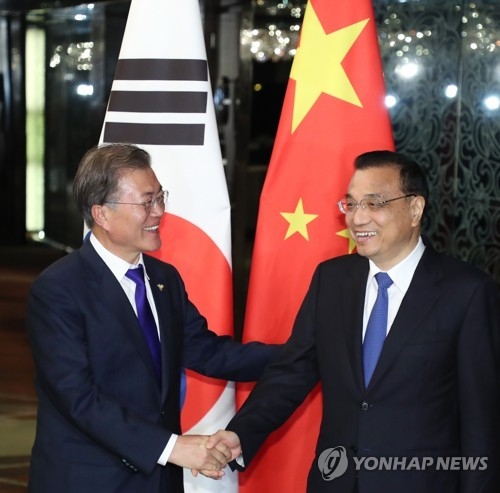 This photo, taken Nov. 13, 2017, shows South Korean President Moon Jae-in (L) and Chinese Premier Li Keqiang shaking hands before the start of their bilateral talks on the sidelines of the Association of Southeast Asian Nations forum in Manila, the Philippines. (Yonhap)