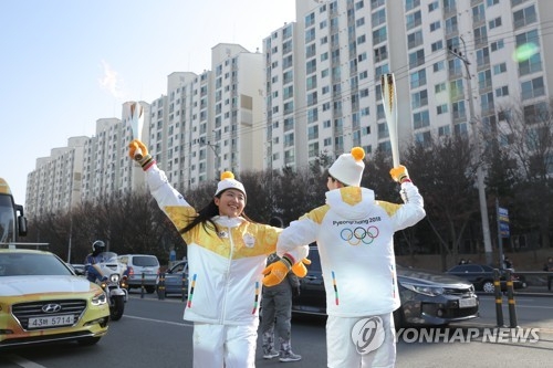 This photo provided by the PyeongChang Olympics organizers shows two torchbearers celebrating in the torch relay for the 2018 PyeongChang Olympic Games in Daegu on Dec. 31, 2017. (Yonhap)