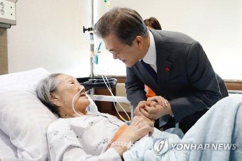 President Moon Jae-in (R) holds a hand of a former South Korean sex slave, Kim Bok-dong, while visiting the 90-year-old at a local hospital in Seoul on Jan. 4, 2018, shortly before his meeting with eight other former sex slaves at his office Cheong Wa Dae. (Yonhap)