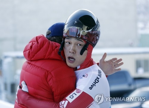 In this Associated Press file photo taken Nov. 18, 2017, Yun Sung-bin of South Korea (R) is congratulated by a team official after winning the men's skeleton race at the International Bobsleigh and Skeleton Federation World Cup in Park City, Utah. (Yonhap)