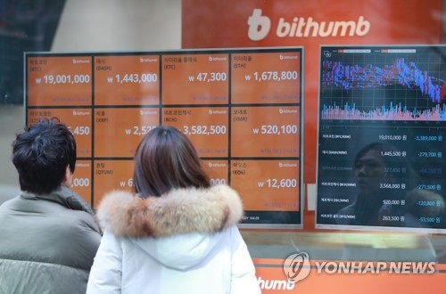 Two people read tables displayed at Bithumb, the largest cryptocurrency exchange in South Korea, in central Seoul on Jan. 11, 2018. (Yonhap) 