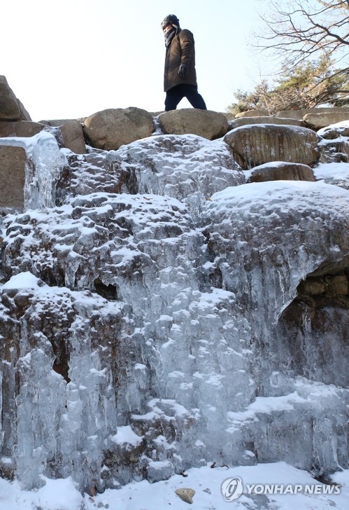 A citizen walks by a frozen waterfall along a trail in Gwacheon, south of Seoul, on Jan. 12, 2018. (Yonhap)
