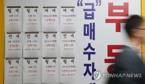 In this file photo taken Oct. 8, 2017, a passerby walks in front of a realtor's office displaying signs for home leases and home sales. (Yonhap)