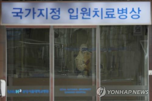 A staff member at Seoul National University Hospital in Bundang, south of Seoul, is in a full protective suit waiting to check people entering the entrance on Jan. 29, 2020. (Yonhap)