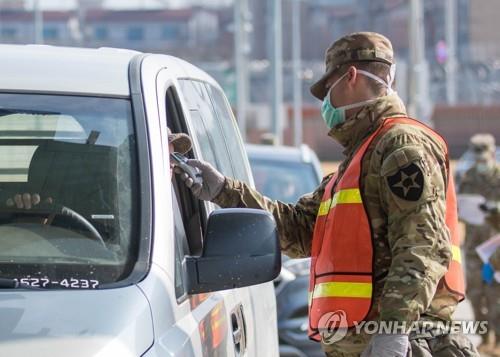 A military guard at U.S. Army Garrison Humphreys in Pyeongtaek, 70 kilometers south of Seoul, checks the temperature of a driver to screen entrants to the compound for the novel coronavirus, on Feb. 28, 2020, in this photo provided by United States Forces Korea. (PHOTO NOT FOR SALE) (Yonhap)