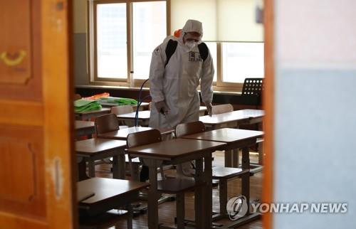 An army conscript disinfects a classroom at an elementary school in the southeastern city of Daegu on May 1, 2020, as part of efforts to prevent coronavirus infections among children. The country is preparing for the physical reopening of schools after weeks of online learning due to the COVID-19 pandemic. (Yonhap)