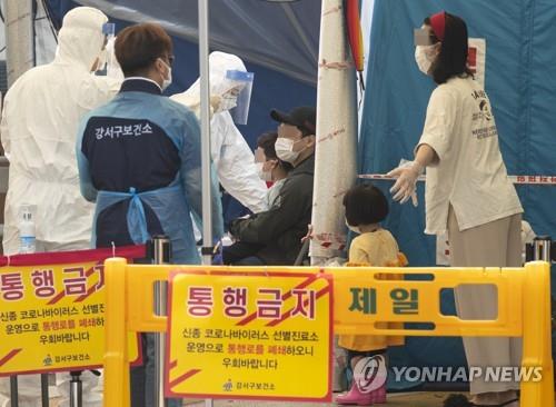 Health workers speak to citizens waiting in line for virus tests at a public medical center in Gangseo Ward, western Seoul, on May 26, 2020, one day after a kindergarten student in the district tested postive for the novel coronavirus. (Yonhap)