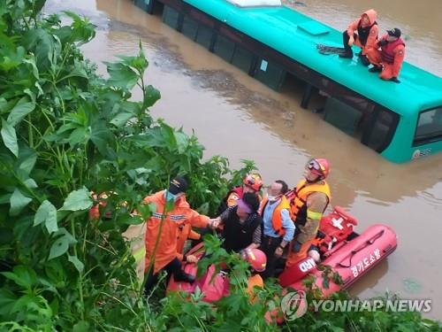 Rescuers assist a boat carrying stranded passengers from a flooded inter-city bus in Paju, north of Seoul, on Aug. 6, 2020, after the bus was caught in a flash flood amid heavy rain, in this photo released by the Paju fire station. (PHOTO NOT FOR SALE) (Yonhap)