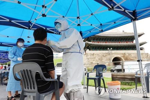 In this photo, taken on Aug. 10, 2020, health workers examine a citizen for a COVID-19 test at a makeshift clinic near Namdaemun Market in Seoul after eight merchants there tested positive for the virus. (Yonhap)