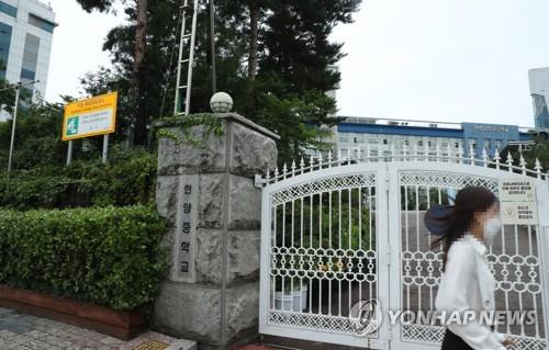 In the file photo taken on July. 14, 2020, a woman walks past the entrance of Hanyang Middle School in Seoul. (Yonhap)