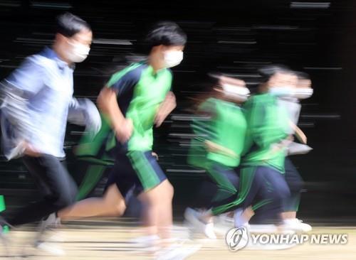 Students wearing face masks run at a school yard in the southern city of Gwangju on Oct. 15, 2020. (Yonhap) 