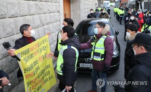 A civic activist demanding stern punishment for former President Chun Doo-hwan talks with police in front of Chun's residence in western Seoul on Nov. 30, 2020. (Yonhap)