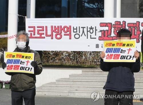 This file photo shows two churchgoers holding signs calling for in-person worship services to be allowed at churches. (Yonhap) 