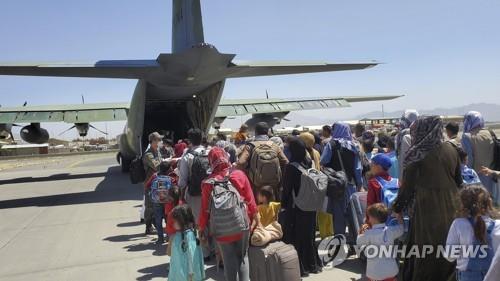 Afghans who have worked for the South Korean government in Afghanistan and their family members line up to board a South Korean military plane at an airport in Kabul, in this photo provided by the Ministry of Foreign Affairs on Aug. 25, 2021. (PHOTO NOT FOR SALE) (Yonhap) 