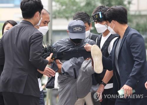 The suspected murderer Kang kicks a microphone held by a reporter when asked about the motive for his alleged crimes outside the Seoul Dongbu District Court in Seoul on Aug. 31, 2021. (Yonhap)