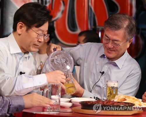This photo shows then Seongnam Mayor Lee Jae-myung (L) sharing beer at a pub in Seoul with now President Moon Jae-in during the Democratic Party presidential primary on April 8, 2017. (Yonhap)