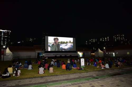 This photo provided by the Busanjin Ward Office of Busan, 450 kilometers southeast of Seoul, shows people watching a film at a public park in "BIFF in the Neighborhood," a program for the local community at the 26th Busan International Film Festival. (PHOTO NOT FOR SALE) (Yonhap) 