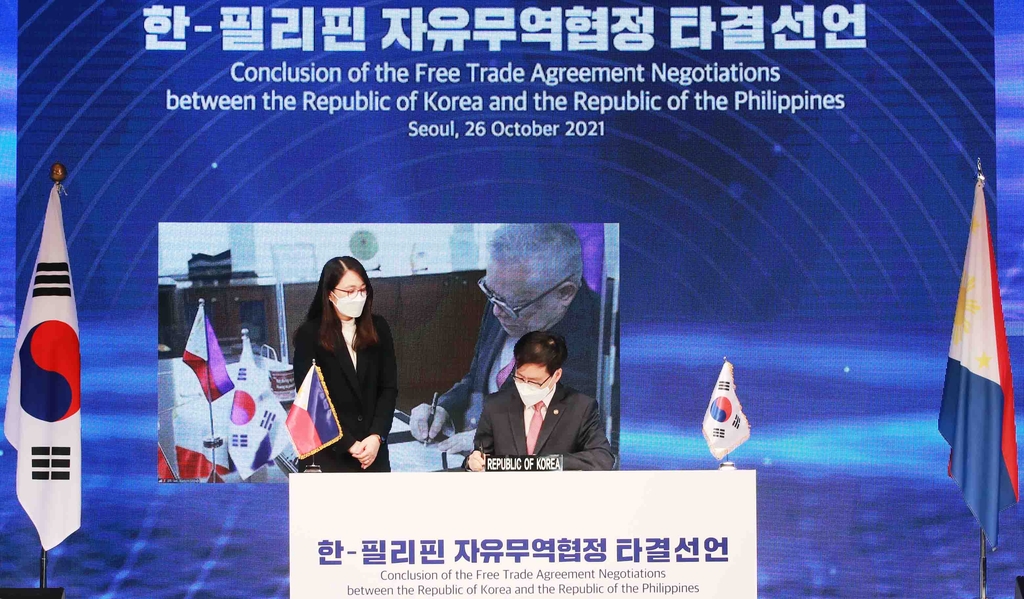 Trade Minister Yeo Han-koo (C) signs a joint statement on the conclusion of the South Korea-the Philippines Free Trade Agreement negotiations during a virtual meeting with his Filipino counterpart, Ramon Lopez, in this photo provided by the Ministry of Trade, Industry and Energy. (PHOTO NOT FOR SALE) (Yonhap) 