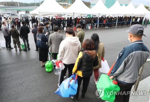 People stand in line to buy urea water solution at an indoor gym in Iksan, North Jeolla Province, southwestern South Korea, on Nov. 9, 2021, amid the nationwide supply shortage of the material, which is used in diesel vehicles to reduce emissions, due to China's sudden export curbs. (Yonhap)