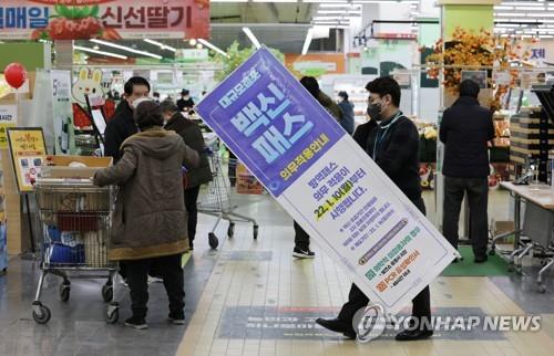 A clerk removes a notice on the government's mandatory vaccine pass system at a retail outlet in Seoul on Jan. 14, 2022, right after the Seoul Administrative Court suspended the vaccine pass system at department stores and retail outlets located in Seoul. Restaurants and cafes, however, were excluded from the suspension. (Yonhap)