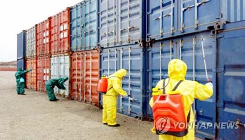 In this March 2020 file photo captured from the website of North Korea's main newspaper, the Rodong Sinmun, workers disinfect cargo containers at the country's western port of Nampo. (PHOTO NOT FOR SALE) (Yonhap) 