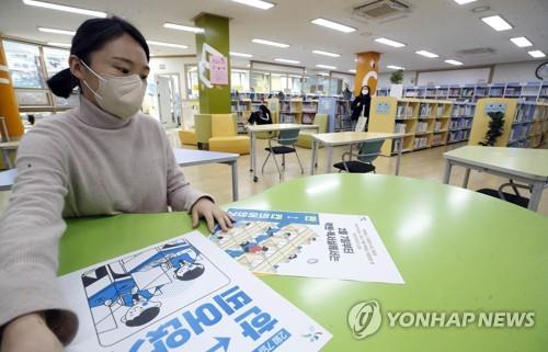 A librarian places a poster about social distancing rules at Unam Library in Gwangju on Feb. 4, 2022, in this photo provided by Gwangju's Buk Ward office. (PHOTO NOT FOR SALE) (Yonhap)