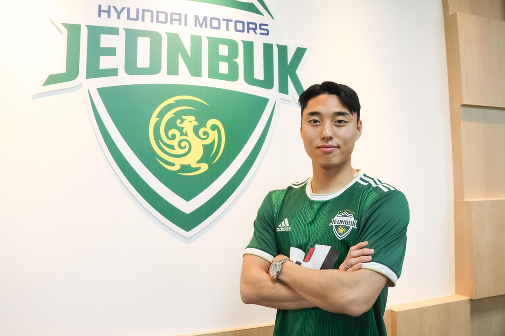 New Jeonbuk Hyundai Motors winger Lee Dong-jun poses in front of the team's logo at Jeonju World Cup Stadium in Jeonju, 200 kilometers south of Seoul, after signing with the K League 1 club on Dec. 22, 2022. Photo courtesy of Jeonbuk. (PHOTO NOT FOR SALE) (Yonhap)