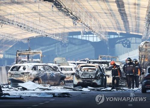 Firefighters examine cars destroyed by a fire the previous day inside an expressway noise-barrier tunnel, just south of Seoul, on Dec. 30, 2022. (Yonhap)