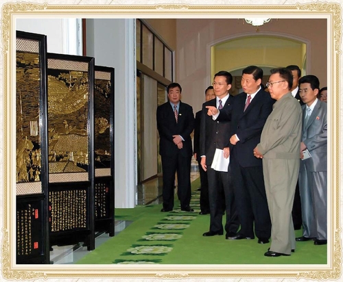 This photo, captured from the website of North Korea's Foreign Languages Publishing House on Jan. 30, 2023, shows former North Korean leader Kim Jong-il (2nd from R) and then Chinese Vice President Xi Jinping (3rd from R) looking at a folding screen gifted by Xi when he visited North Korea in 2008, in a photo book of gifts given to Kim. (PHOTO NOT FOR SALE) (Yonhap)