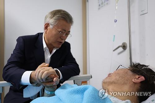 Former President Moon Jae-in (L) holds opposition leader Lee Jae-myung's hand during his visit to a hospital in Seoul on Sept. 19, 2023. Moon urged Lee to end a hunger strike he has been on for nearly three weeks in protest against government policies. (Yonhap)
