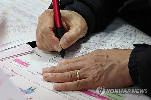 Una persona mayor que busca empleo llena un formulario de solicitud en una feria de empleo en Seúl el 13 de diciembre de 2023. (Yonhap)