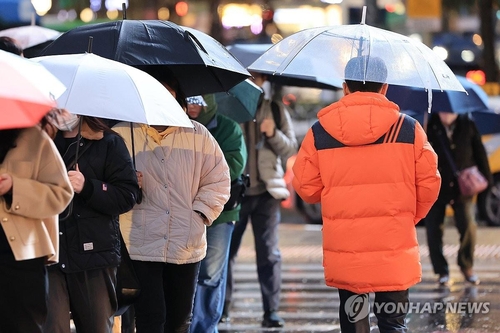 This photo taken Nov. 26, 2024, shows people in winter coats walking amid rain in central Seoul. (Yonhap)