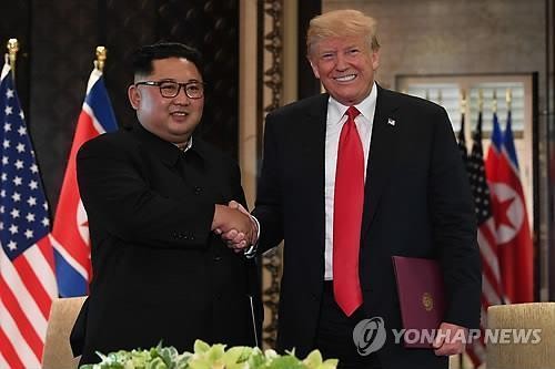 Esta fotografía de archivo de la AFP muestra al presidente estadounidense, Donald Trump (derecha), estrechando la mano del líder norcoreano, Kim Jong-un, después de firmar una declaración conjunta en el hotel Capella de la isla Sentosa, en Singapur, el 12 de junio de 2018. (Yonhap)