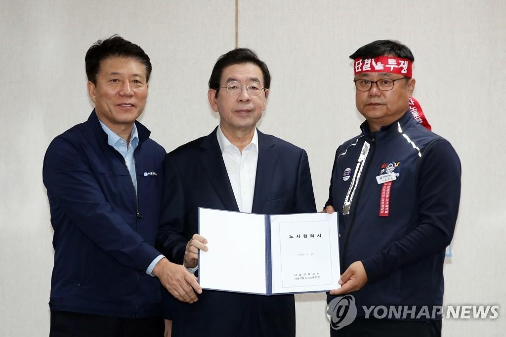 Le PDG de Seoul Metro Kim Tae-ho (à g.), le maire de Séoul Park Won-soon (au c.) et le leader du syndicat de Seoul Metro Yoon Byung-beom posent au siège de l'entreprise à Séoul, le mercredi 16 octobre 2019.