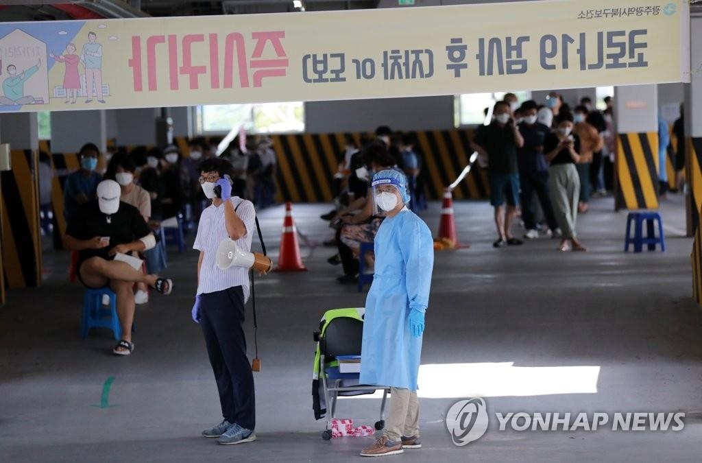 Les agents de santé se préparent à travailler alors que les citoyens font la queue dans une clinique de dépistage du virus à Gwangju, le 28 août 2020.