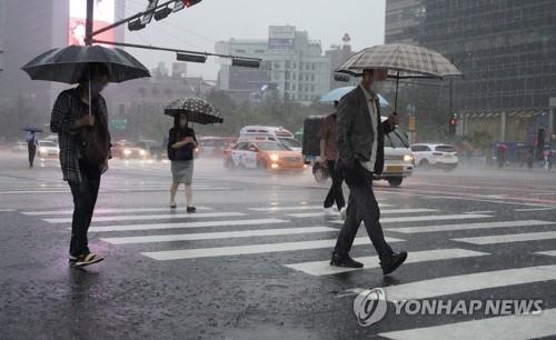 Des personnes portant un parapluie traversent un passage piéton au carrefour de Gwanghwamun, dans le centre de Séoul, pour se diriger vers leur bureau sous une forte pluie, le jeudi 30 juin 2022.