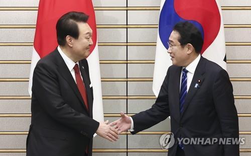 Le président sud-coréen Yoon Suk Yeol (à gauche) et le Premier ministre japonais Fumio Kishida se serrent la main avant leur sommet élargi à la résidence de ce dernier à Tokyo, le 16 mars 2023.